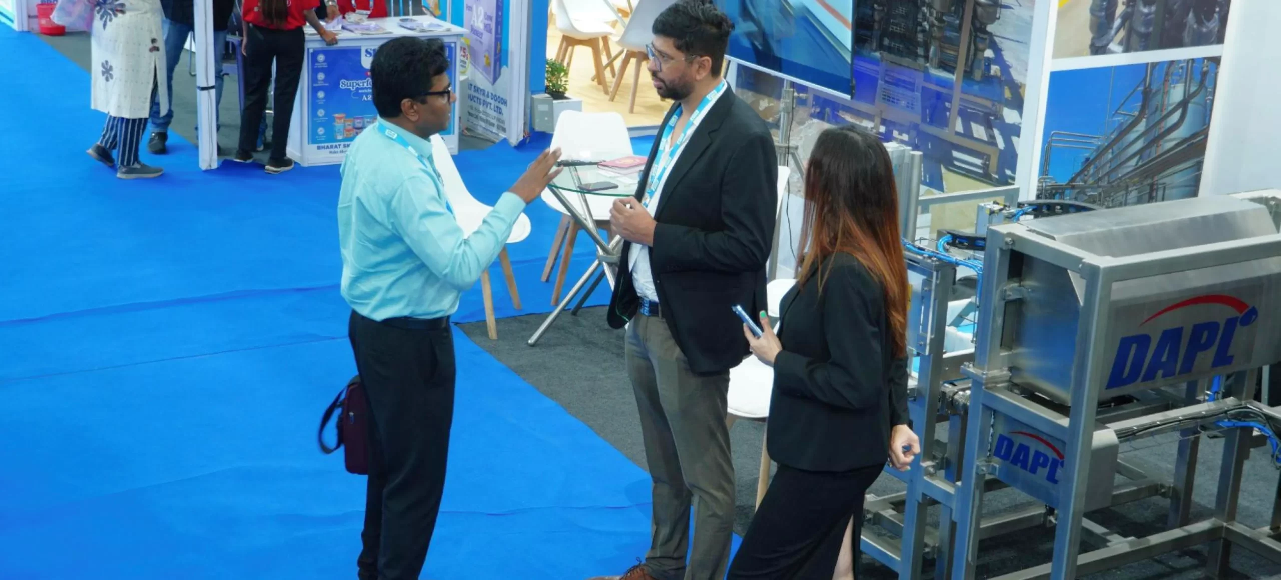 DAPL team interacting with a visitor at Inter Dairy Expo 2024 in Mumbai, showcasing advanced dairy processing equipment at their exhibition booth