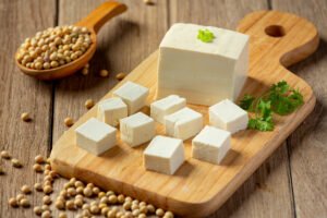Fresh paneer cubes on wooden board with soybeans, representing hygienic dairy production